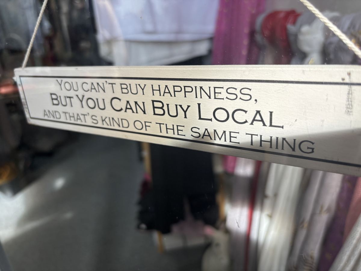 A wooden sign in the shop reading: you can't buy happiness, but you can buy local, and that's kind of the same thing