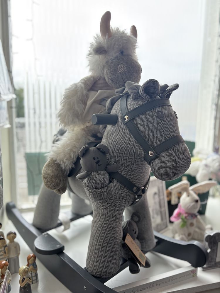 A grey herringbone rocking horse toy in the shop