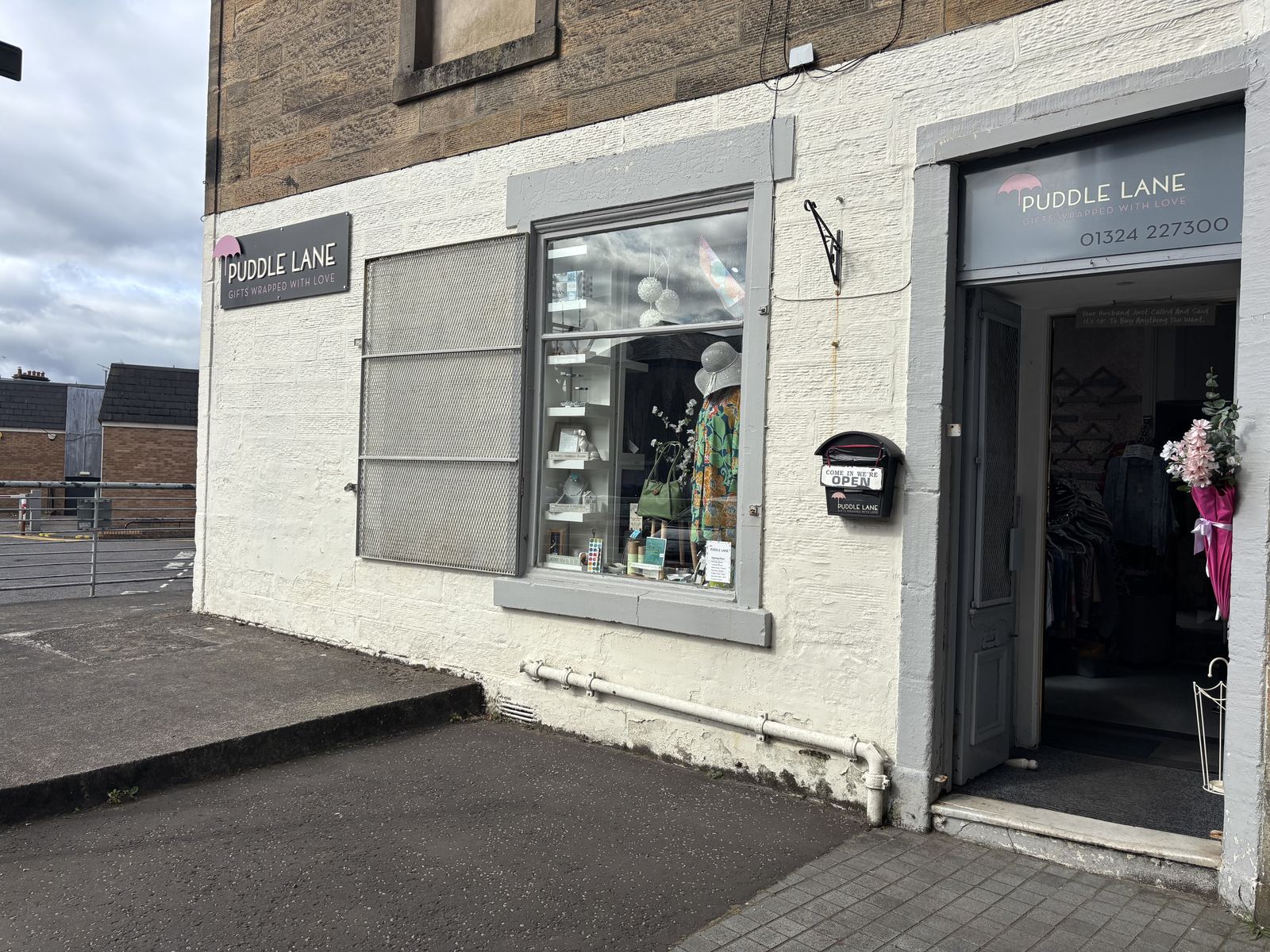 The Puddle Lane shopfront on Falkirk High Street: white walls, grey trim, the Puddle Lane sign with its pink umbrella, and the door standing open