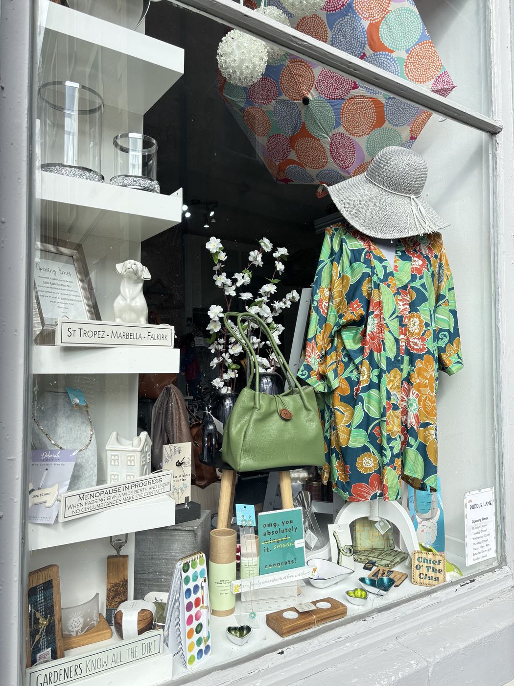 Puddle Lane's shop window, with the opening times card and a display of gifts
